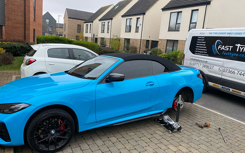 Blue sports car with  Fast Tyre van in background