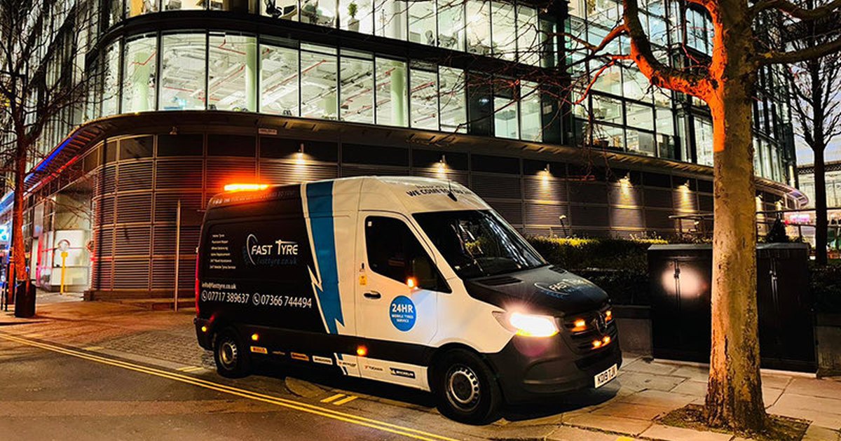 Fast Tyre van with its amber beacon lit, parked on a London street at night