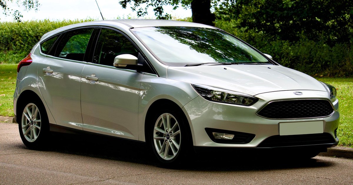 Silver Ford Focus hatchback parked in daylight with greenery behind it