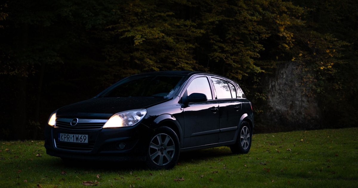 Black Vauxhall Astra parked on grass at twilight