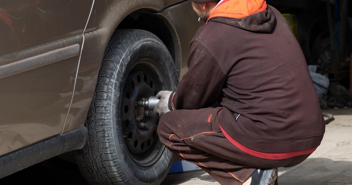 Technician fitting a new tyre at a customer home on a residential driveway