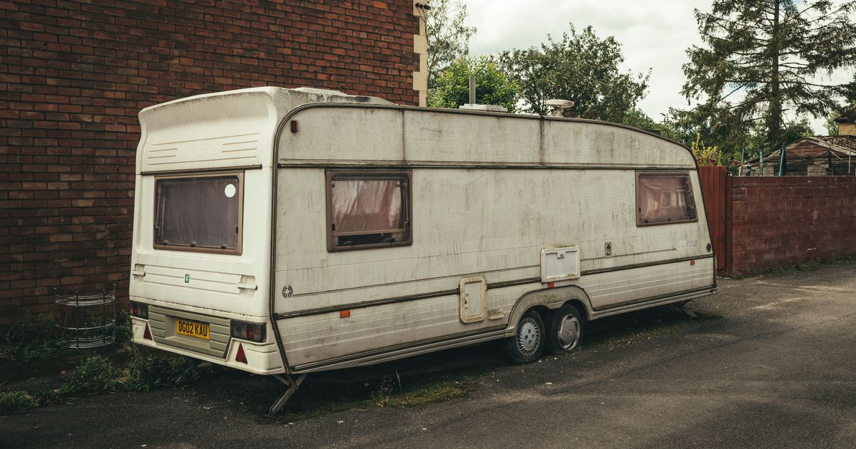 Caravan parked roadside being checked for tyre age and pressure before towing