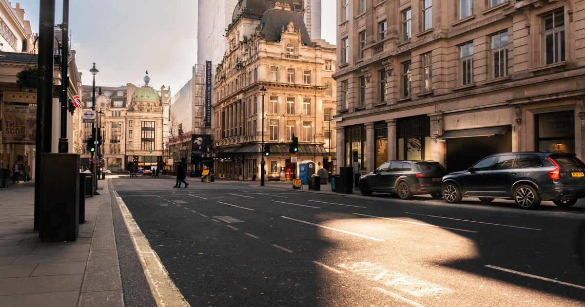 Sunlit London street with traffic and Victorian buildings