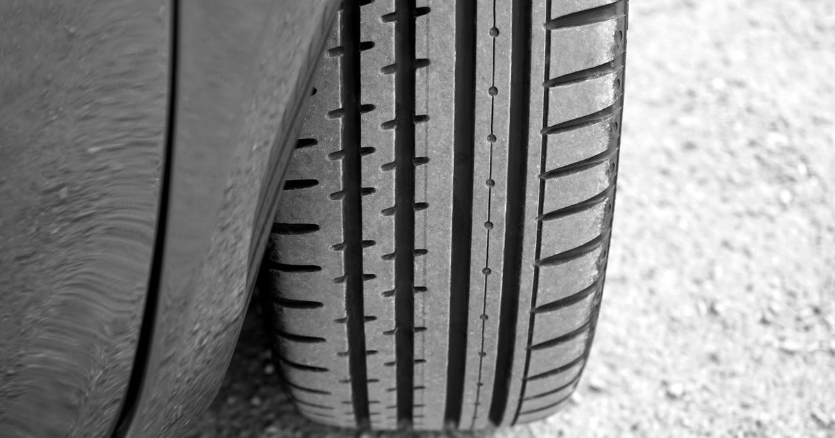 Technician inspecting a car tyre tread for the legal 1.6mm minimum depth in the UK