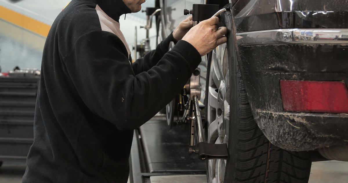 Mobile tyre fitter fitting a new tyre on a driveway with a van behind
