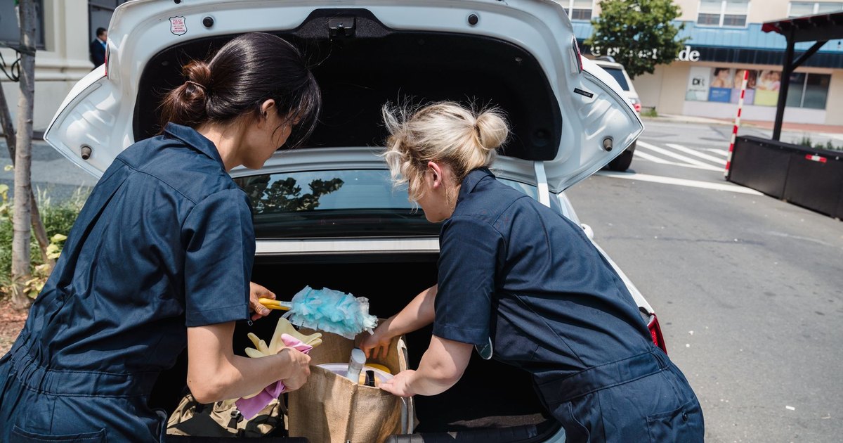 Two people unloading equipment from an open car boot