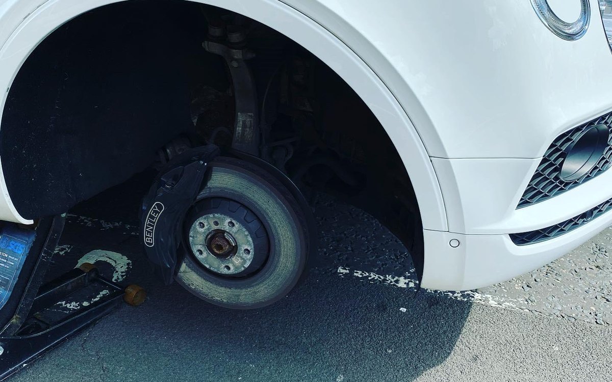 A close-up of a white Bentley with the wheel off and the hub exposed, serving Mayfair, Greater London