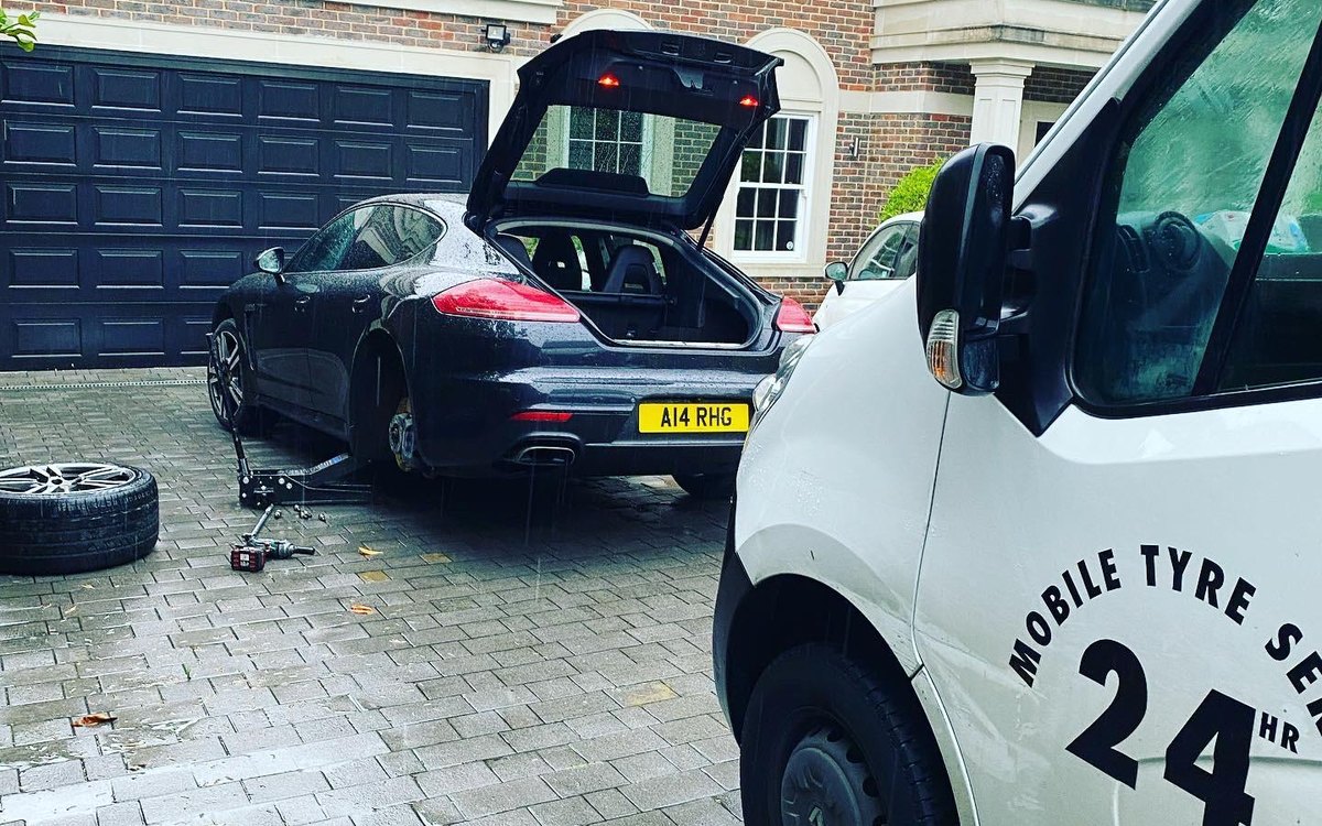 A Fast Tyre van marked 24hr mobile tyre service beside a car having its wheel changed
