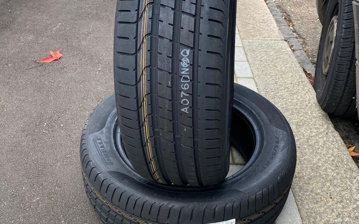 Two new tyres standing on the pavement beside a customer car