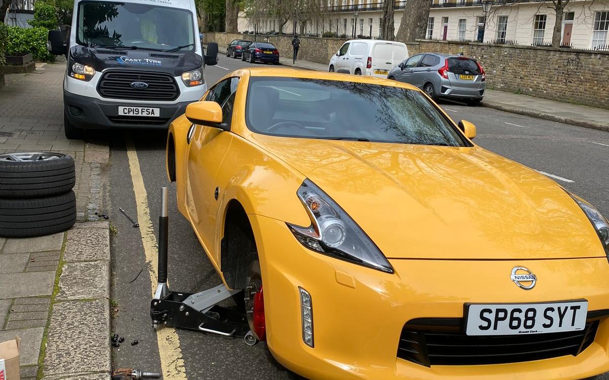 A yellow Nissan 370Z on a London street with a Fast Tyre van parked behind