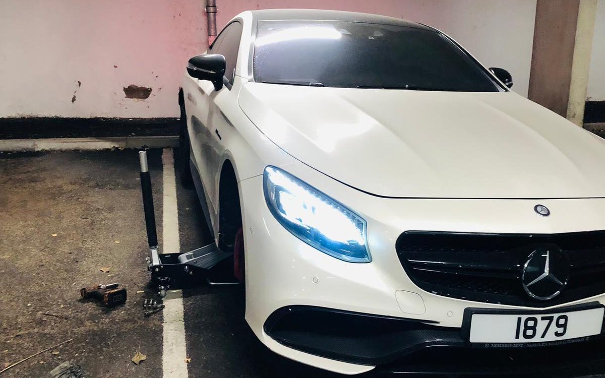 A white Mercedes coupe in an underground car park during a wheel change