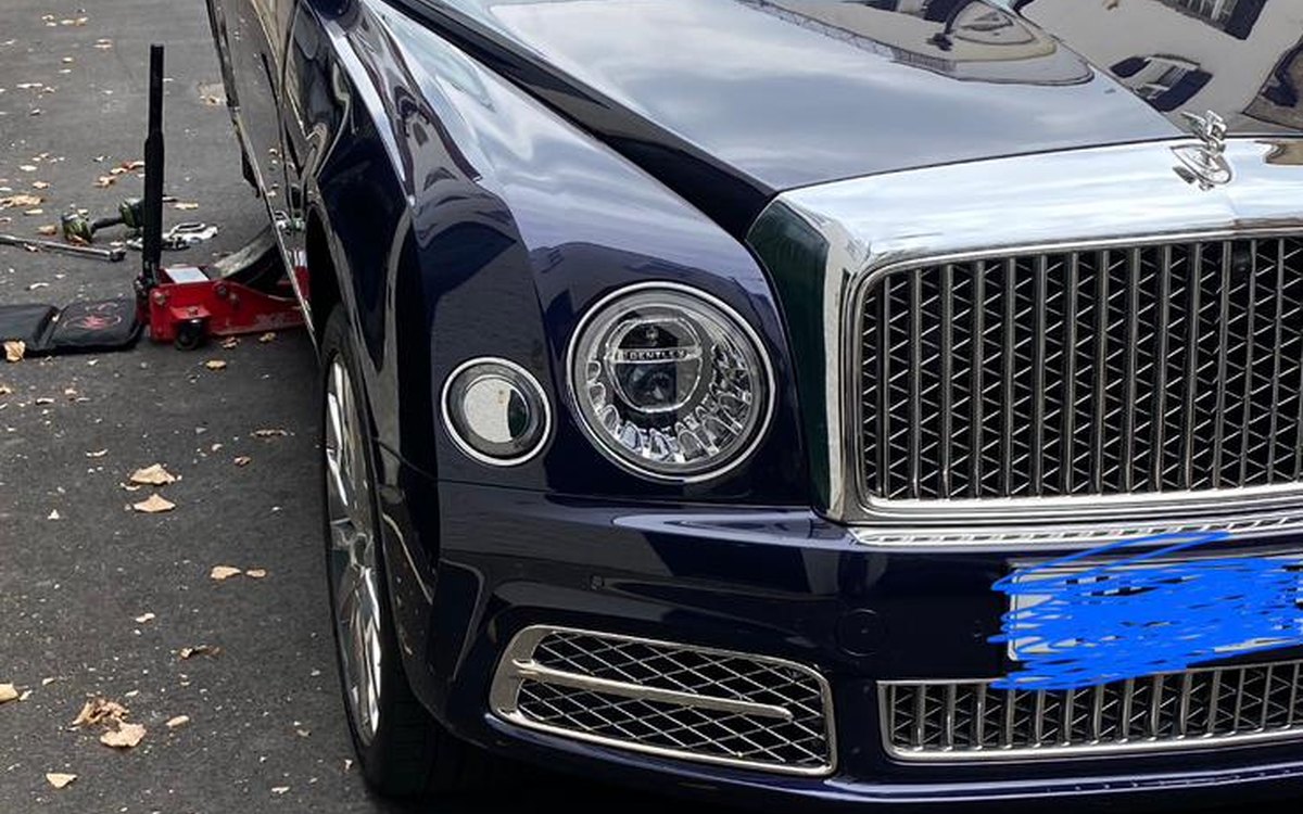 A Bentley on a London street with the wheel removed and tools on the road, serving Tolworth, Greater London