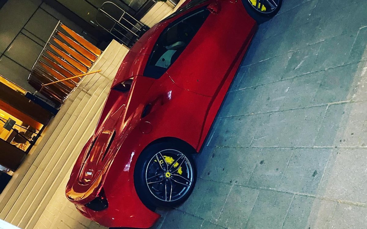 A red Ferrari seen from above in a garage during a tyre change, serving Ashtead, Surrey