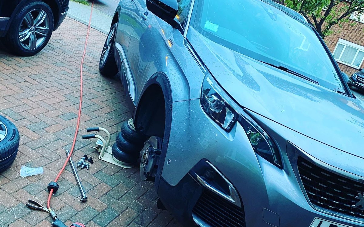 A Peugeot SUV on a driveway with the air line run out and tools ready