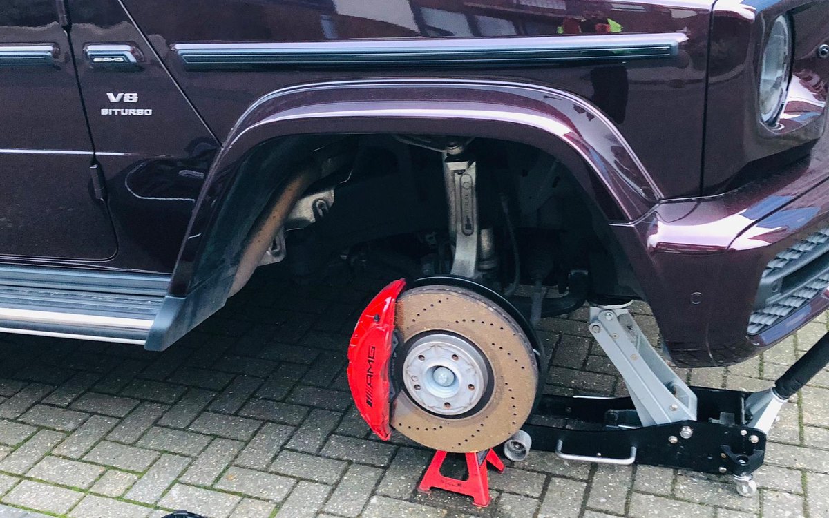 A Mercedes G-Class on a jack with the wheel off and the red brake caliper exposed